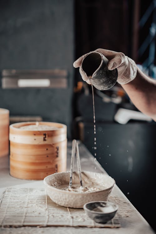 Person Pouring Water on Bowl of Flour