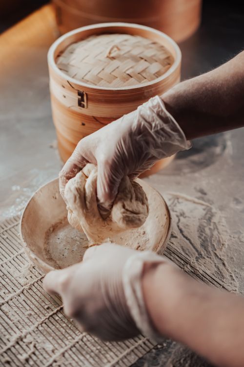 Free Close-up of hands kneading dough on a wooden surface with flour for food preparation. Stock Photo