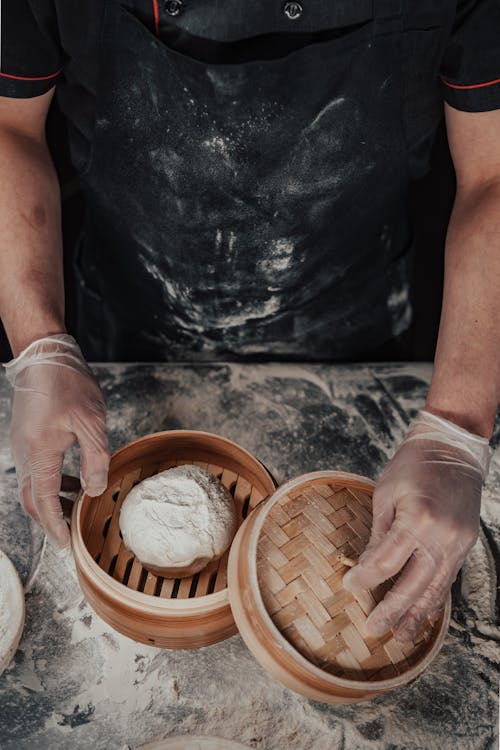 Person Placing Dough in a Bamboo Steamer