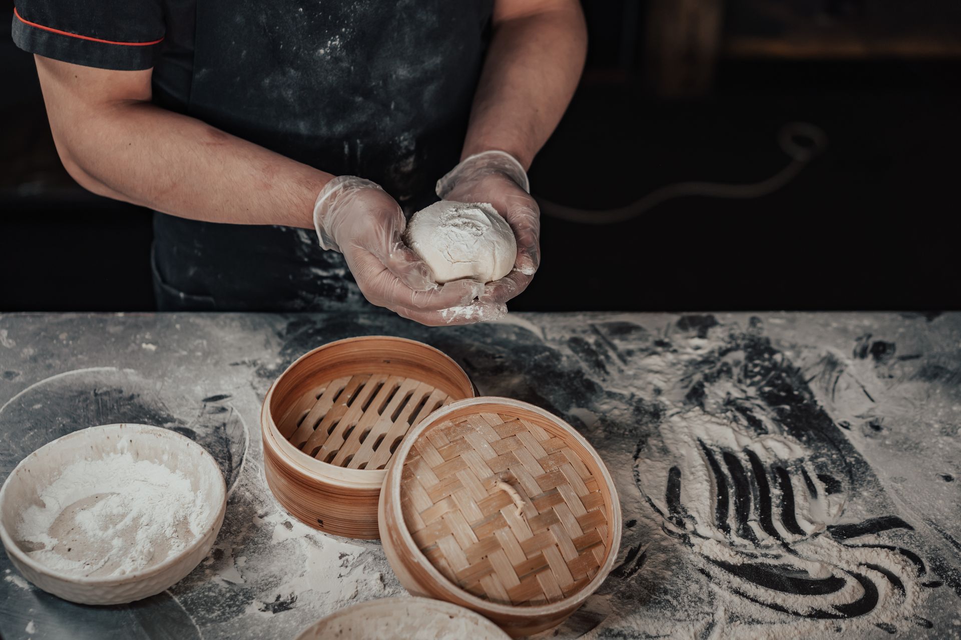 Kitchen Table with Baozi Steamer Baskets, and a Chef Making a Dough