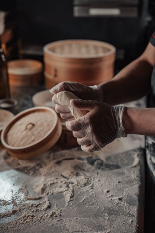 Free Chef skillfully shaping dumplings on a floured table in a kitchen scene. Stock Photo