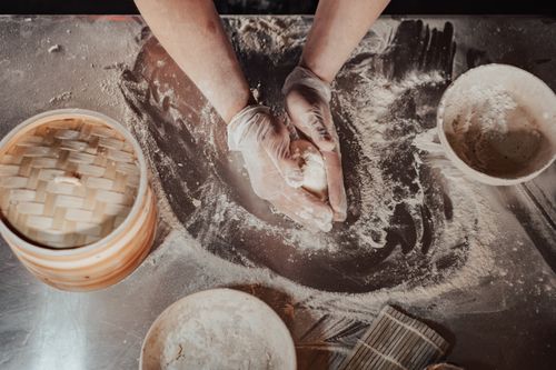 Free Top view of a chef preparing dough with gloves in a flour-covered kitchen setting. Stock Photo