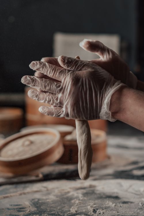 Free Gloved hands skillfully knead dough for making delicious dumplings indoors. Stock Photo