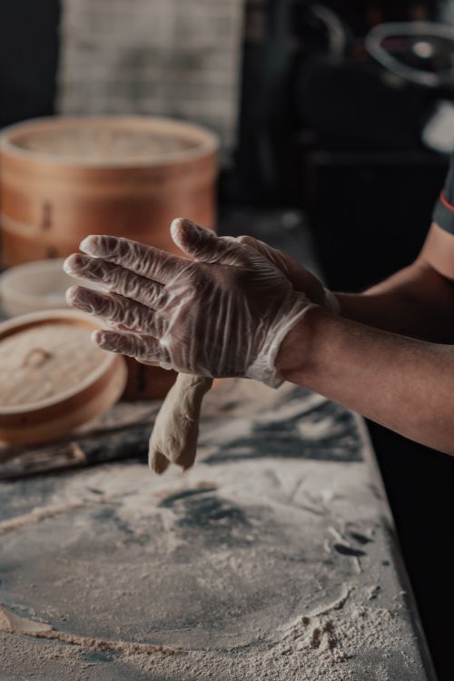 Free Close-up of gloved hands skillfully preparing dumplings in a kitchen setting. Stock Photo