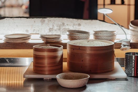 Close-up of bamboo steamers and kitchenware on a metallic countertop.