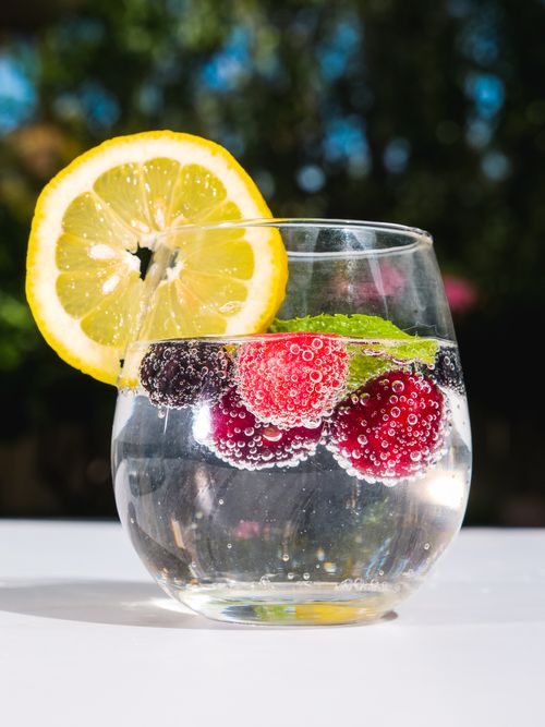 Free A vibrant glass of sparkling water with fresh berries and a lemon slice, perfect for a refreshing drink. Stock Photo