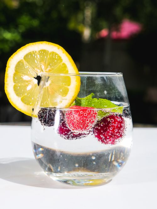 Free Close-up of sparkling water with lemon, cherry, and a mint leaf, vibrant and refreshing. Stock Photo