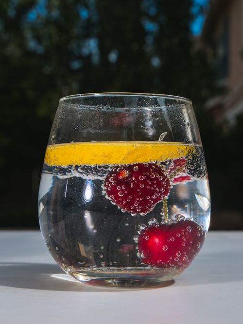 Free Close-up of a glass with sparkling water, raspberries, and lemon slice, refreshing and vibrant. Stock Photo