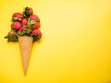 Strawberries in a waffle cone against a bright yellow background, symbolizing freshness and summer.