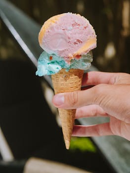 Close-up of a colorful ice cream cone held outdoors with blurred background.