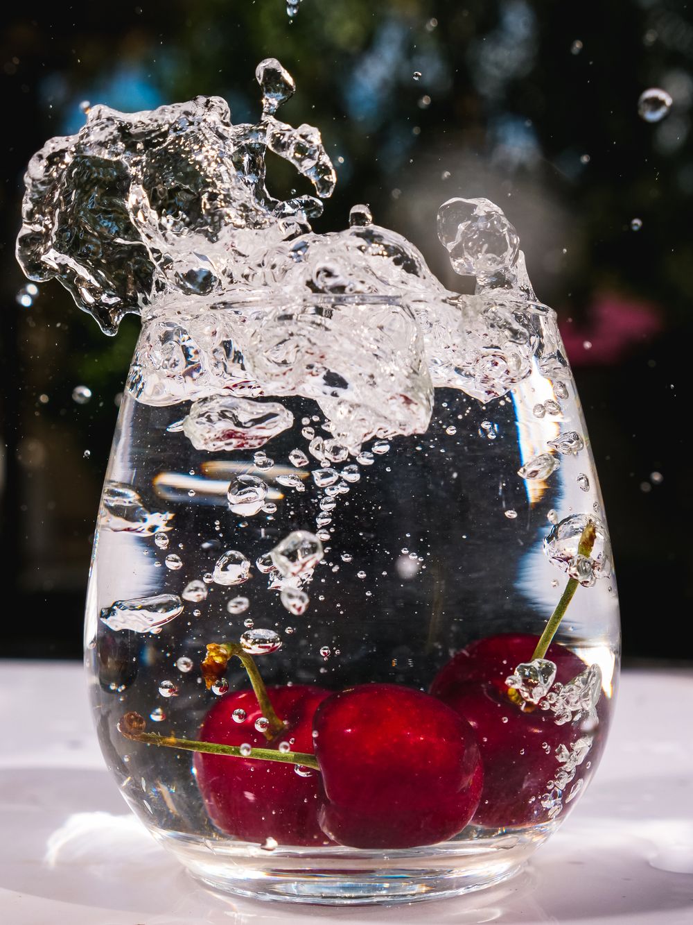 Cherries splashing into a clear glass of water