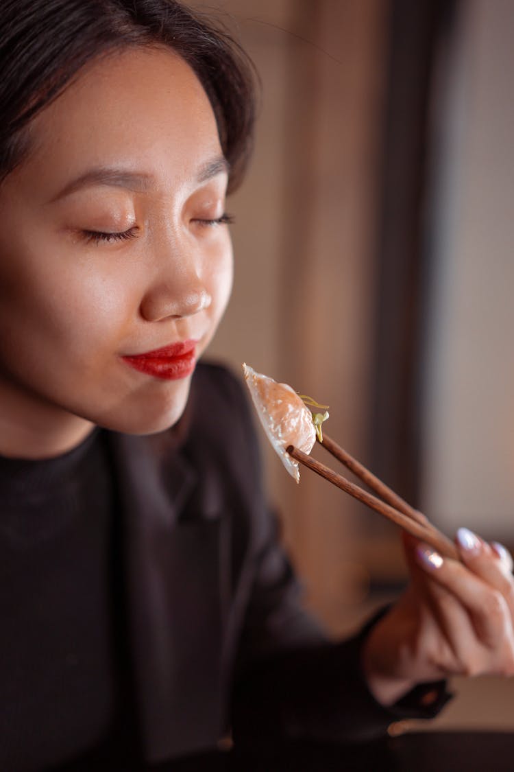 Woman In Black Shirt Eating Dumpling With Chopsticks