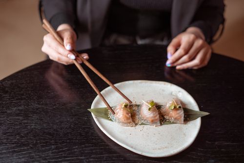 Free Photograph of dimsum being picked up with chopsticks, highlighting Asian cuisine culture. Stock Photo