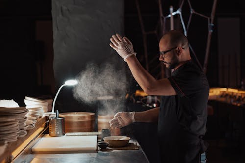 A Man in Black Uniform Sprinkling the Flour