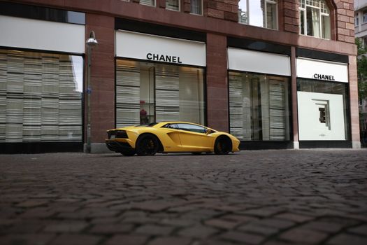 A sleek yellow sports car parked in front of a Chanel store, showcasing luxury and style.