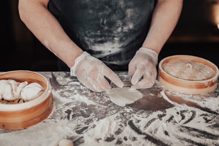 A Person Making A Dumpling While Wearing Gloves