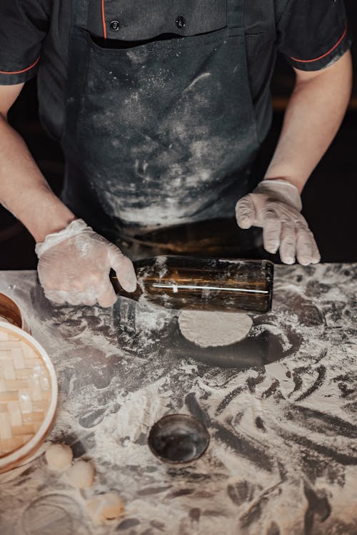Free A Person Wearing an Apron while Holding a Glass Bottle Stock Photo