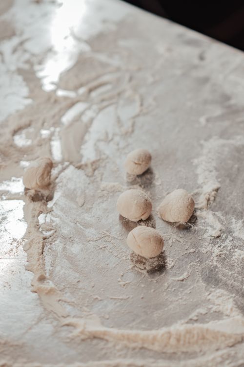 Free A close-up view of dough balls on a floured surface, ready for dumpling preparation. Stock Photo