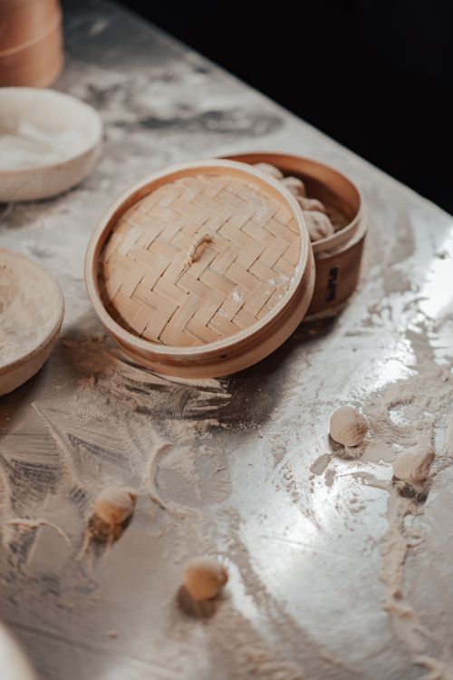 Free A close-up of bamboo steamers and flour-dusted dumpling dough on a metal table, showcasing traditional Chinese cooking. Stock Photo