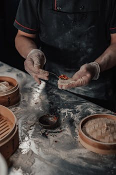 A chef skillfully prepares dumplings with precision on a flour-dusted kitchen counter.