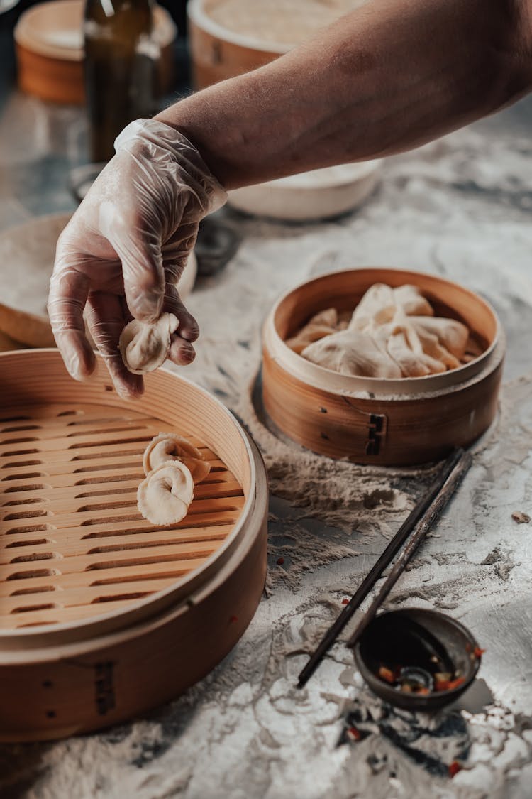 Close-Up Shot Of A Person Putting A Dumpling In A Wooden Tray