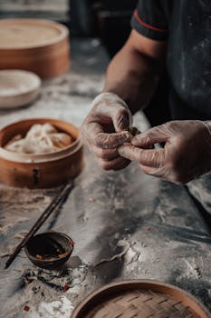 A chef prepares dumplings with precision in a rustic kitchen setting.