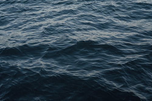 From above of wavy dark blue ocean with ripples on surface in daytime