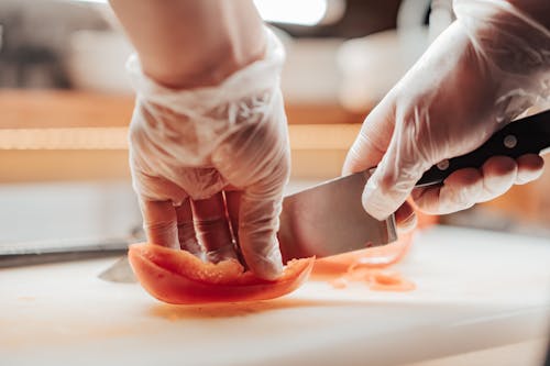 Person Slicing Bell Pepper on White Chopping Board