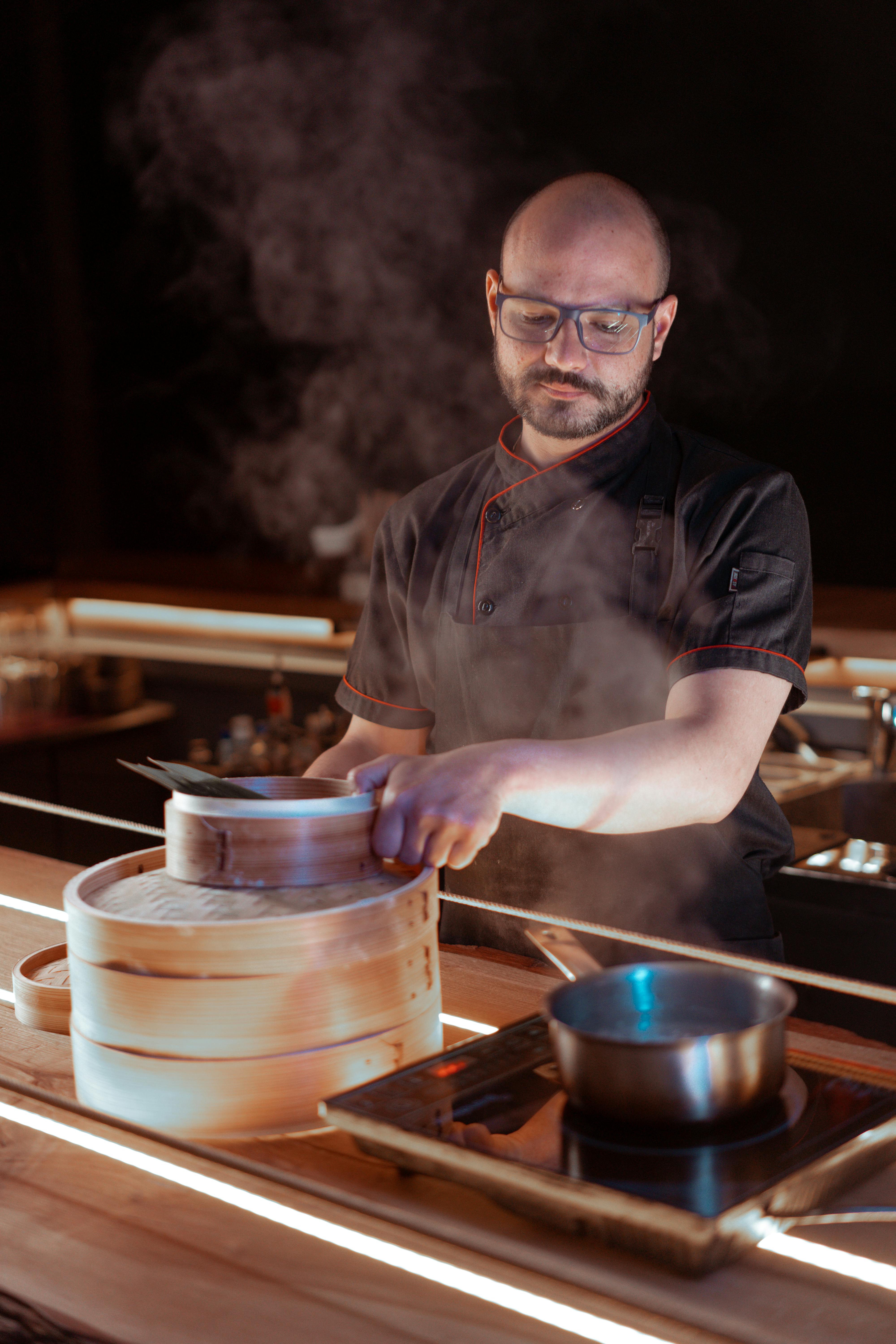 a chef cooking using a saucepan and bamboo steamer