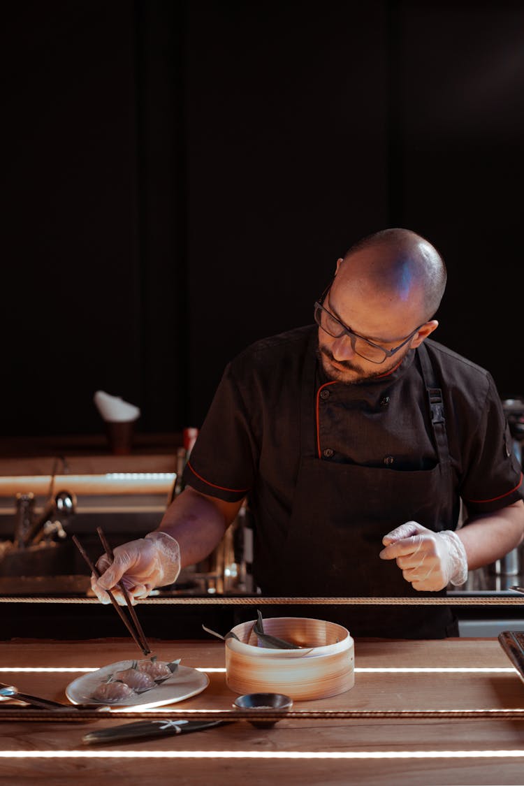 A Man Holding A Chopsticks While Preparing Food