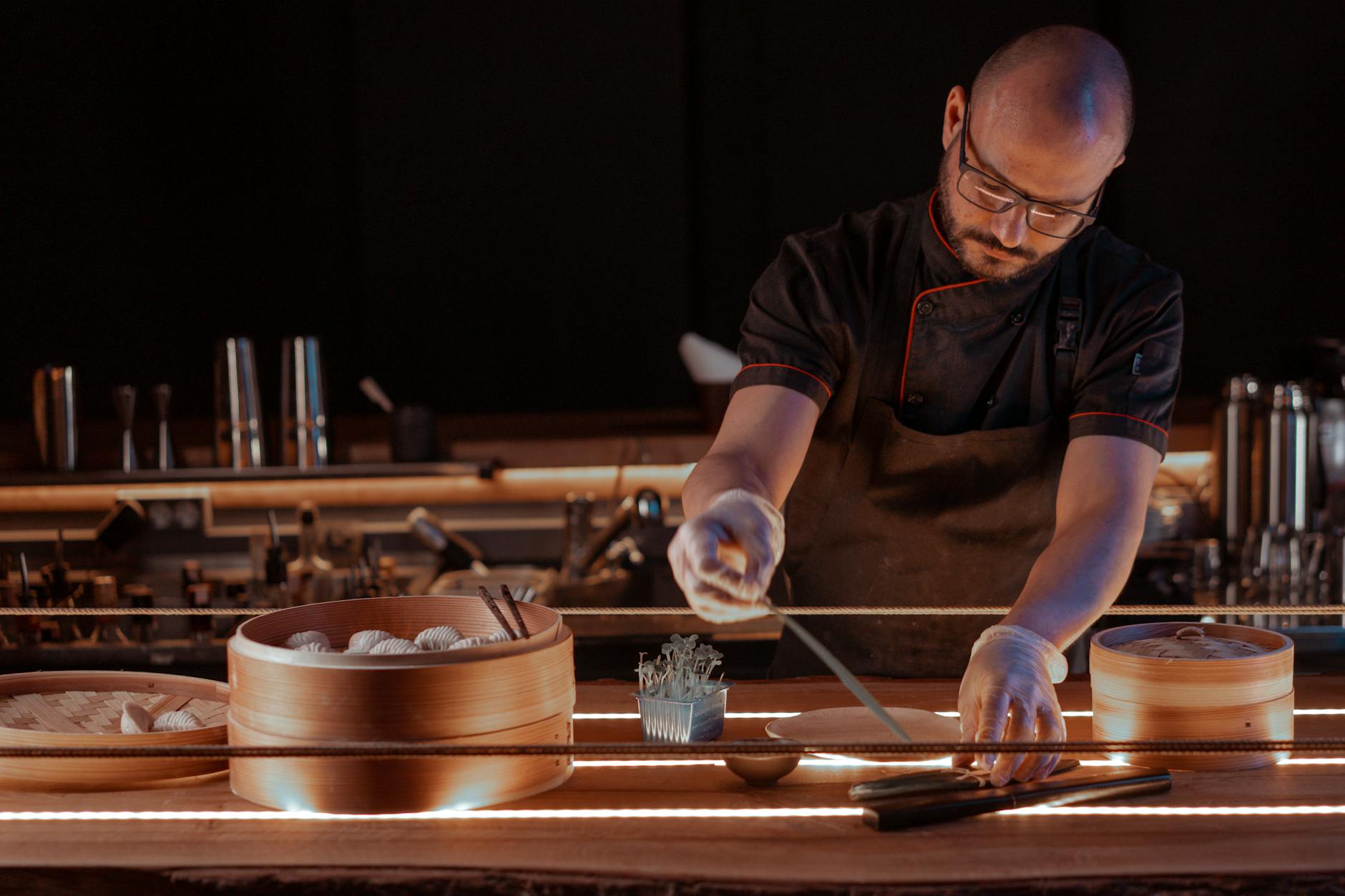 Chef in a restaurant kitchen preparing dumplings using bamboo steamers and chopsticks. Chef in a restaurant kitchen preparing dumplings using bamboo steamers and chopsticks.