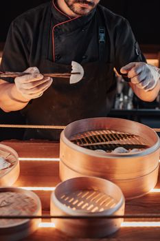 Chef uses chopsticks to handle homemade dumplings, showcasing traditional Chinese cooking.