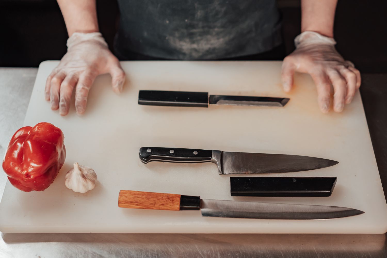 Kitchen knives arranged on a cutting board beside fresh ingredients