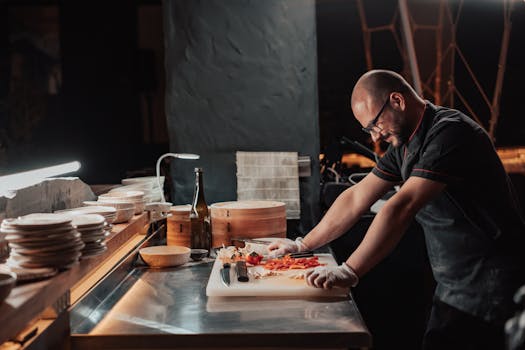 Chef slicing vegetables on a chopping board in a restaurant kitchen under ambient lighting.