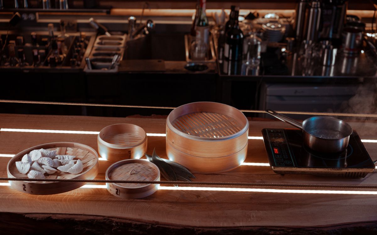 An inviting kitchen setup featuring bamboo steamers, dumplings, and a pot on an induction stove.