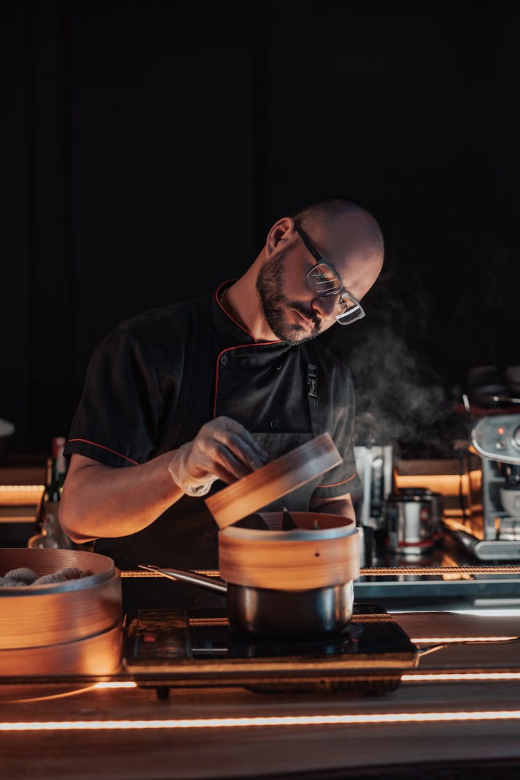 Man In Black Uniform Opening Lid Of A Bamboo Steamer