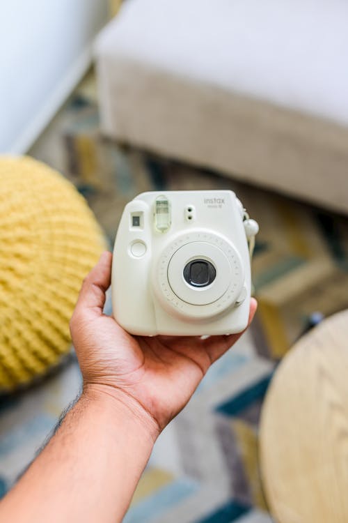 Photo of a Person's Hand Holding a Light Green Instant Camera
