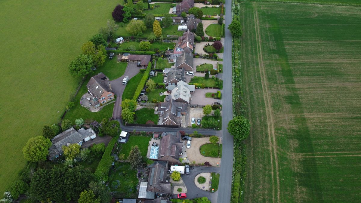 Aerial view of a British village with residential houses and green fields