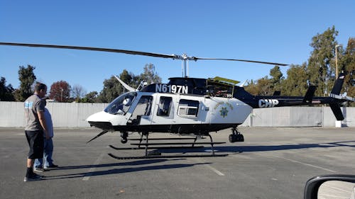 Photo of Two Person Standing in Front of White and Black Helicopter