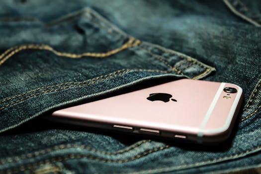 Close-up shot of a rose gold smartphone partially concealed in a denim pocket.