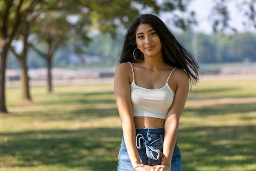 Selective Focus Photo of a Woman in a White Spaghetti Strap Top Looking at the Camera