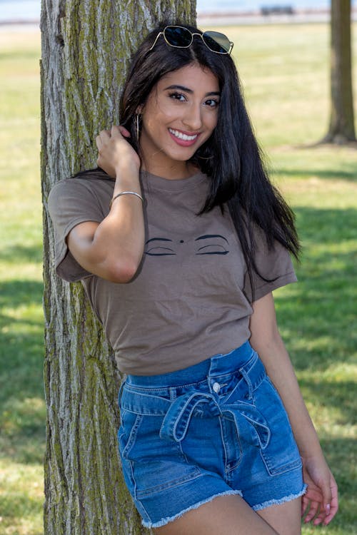 Woman in a Brown Crew Neck Shirt Leaning on a Tree