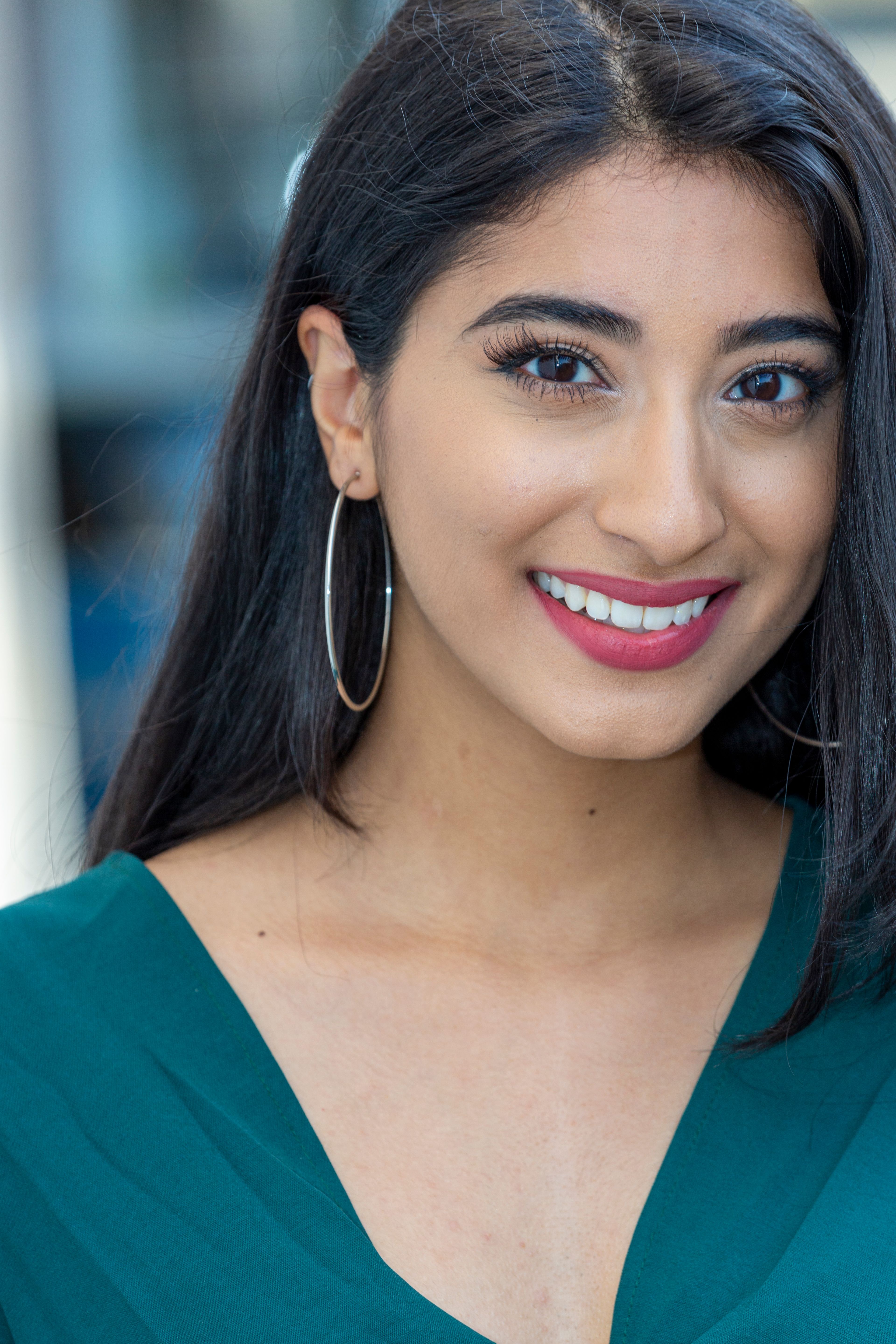 Close-up headshot of a smiling woman with hoop earrings, conveying warmth and friendliness.