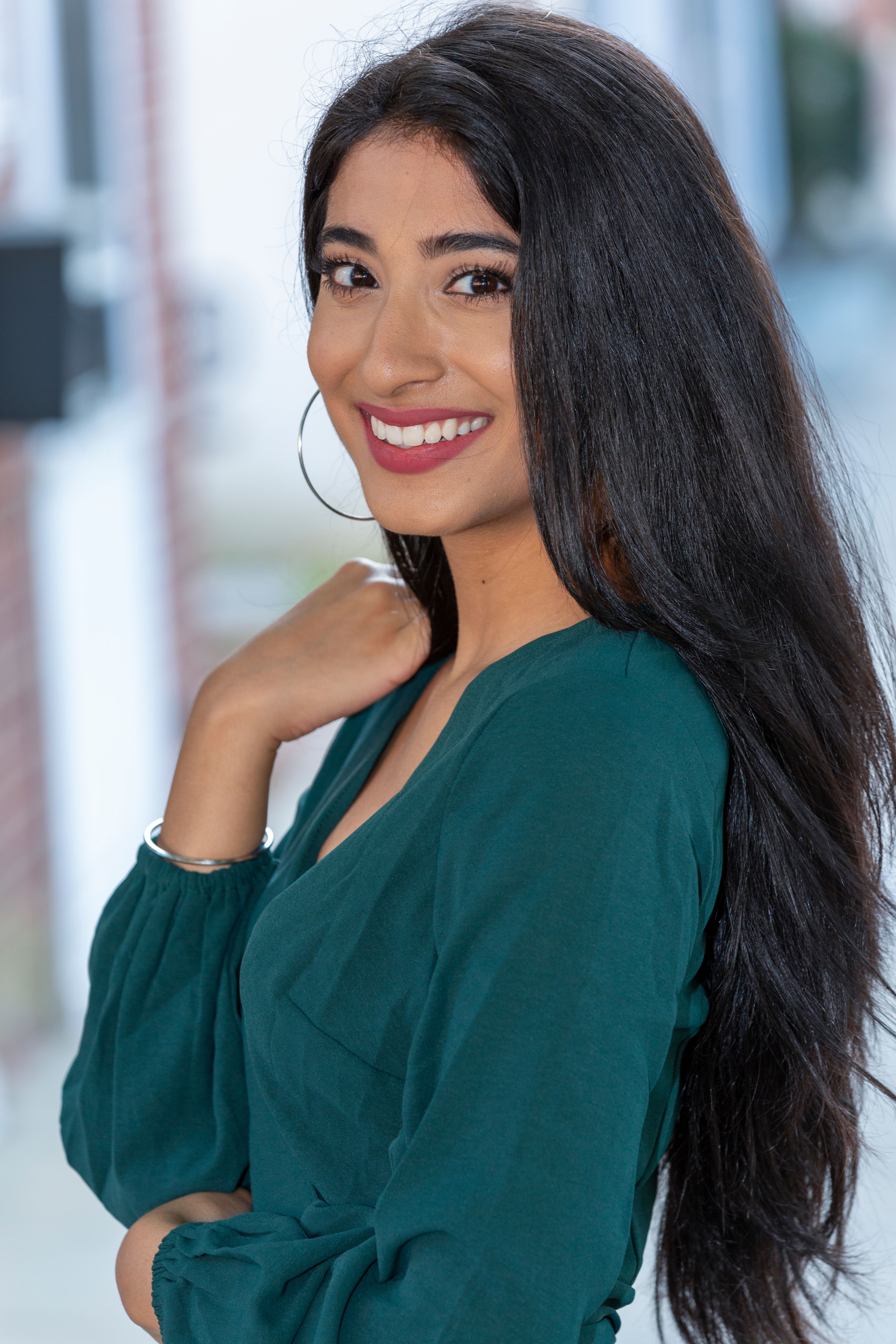 A vibrant portrait of a smiling woman with long hair outdoors.