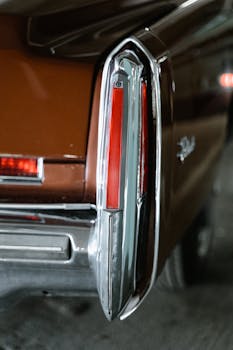 Close-up of a classic car's red taillight with chrome details in a vertical shot.