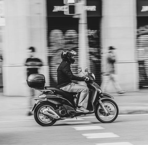 Free Grayscale image of a motorcyclist riding through the bustling streets of Barcelona, capturing motion blur. Stock Photo