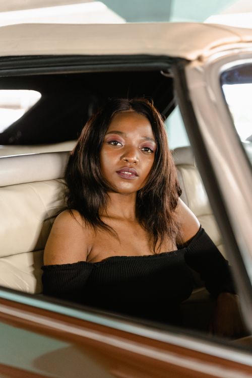 Free Confident woman sitting inside a vintage car, exuding elegance and style. Stock Photo