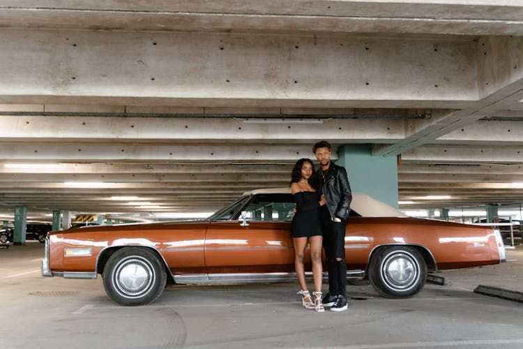 A Couple Standing Together Near A Vintage Car