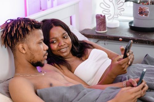 Free Young black couple lying in bed, using smartphones, showcasing modern intimacy and connection. Stock Photo