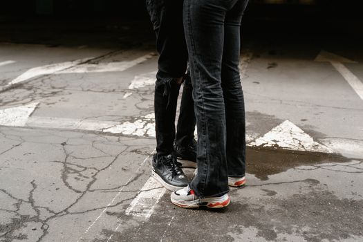 Close-up of two people standing together in casual streetwear on an urban cracked pavement.